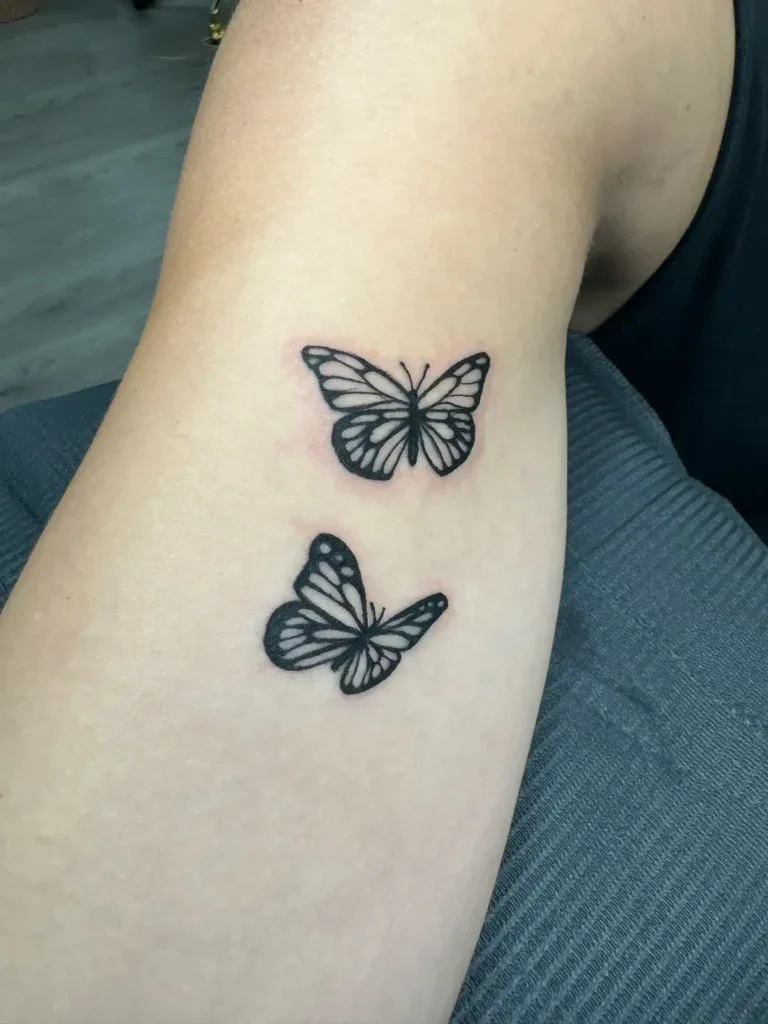 Fine-line butterfly tattoos on an inner arm — precise linework in healed skin